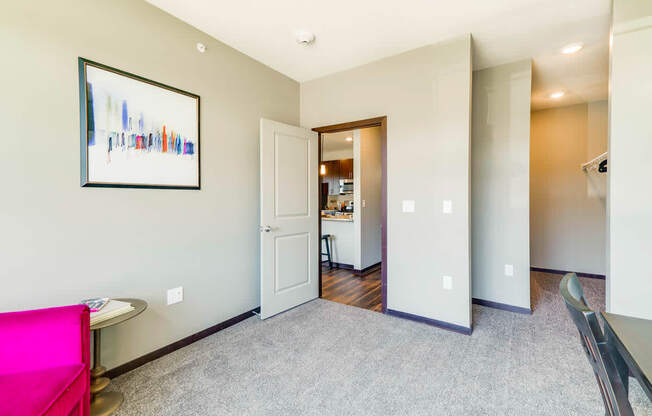 A living room with a pink couch and a painting on the wall.