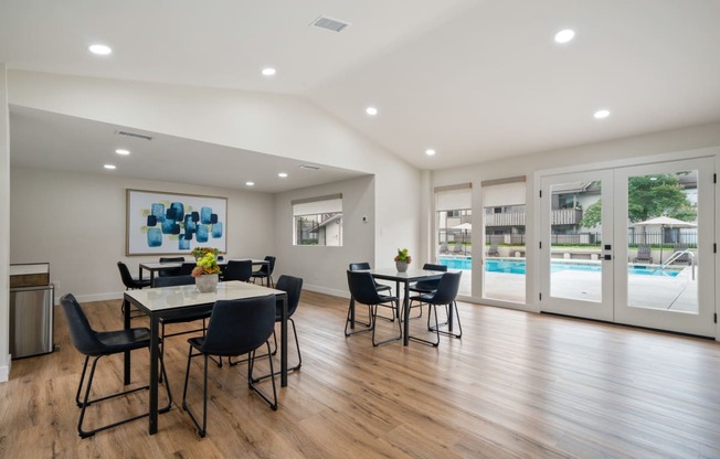 a resident clubhouse with tables and chairs and a pool in the background