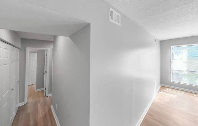 the living room and dining room of an apartment with white walls and wood floors