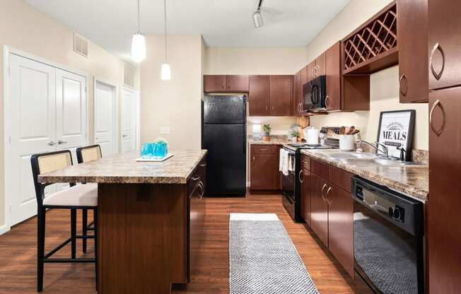 a kitchen with a large island and a black refrigerator