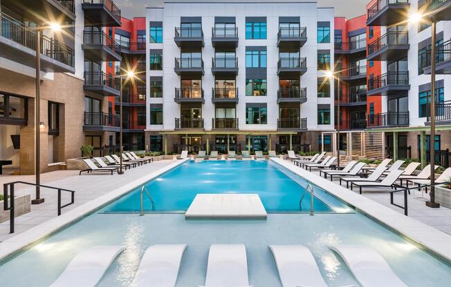 Resort-style pool courtyard with in-water loungers, sundeck seating, and private balconies surrounding the space.