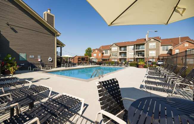 a swimming pool with lounge chairs at an apartment complex