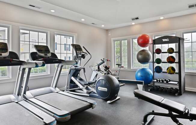 a gym with treadmills and other exercise equipment and windows