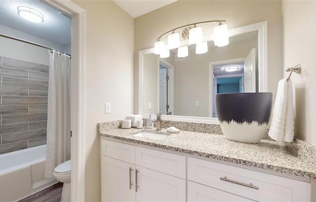 A bathroom with a marble countertop and a large mirror. at Vinings RiverVue, Georgia
