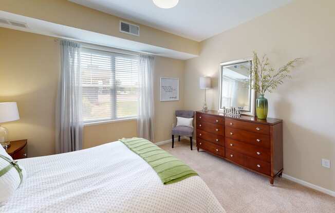 a bedroom with a large window and a dresser with a mirror