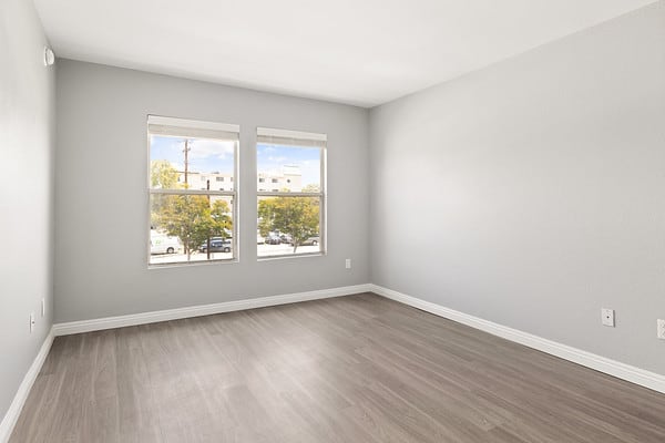 an empty room with wood floors and two windows at NOHO GALLERY Apartments, North Hollywood , CA 91601