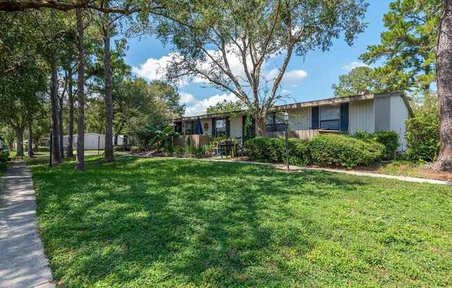 A grassy area with a walking path and trees in front of a building.