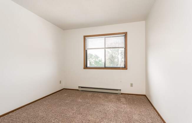 Grand Forks Harrison Apartments. A bedroom with carpet and a window