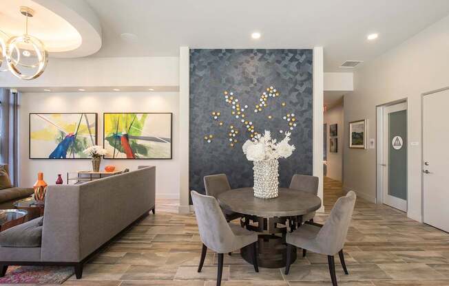 A grey couch sits in front of a grey and white wall with a painting on it.
