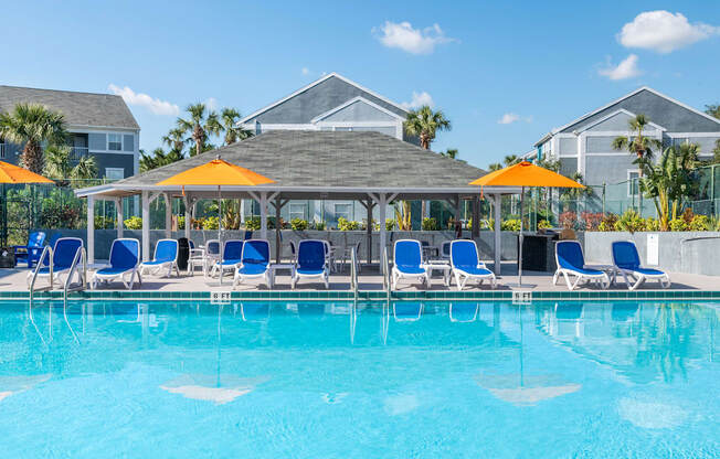 a swimming pool with blue chairs and yellow umbrellas