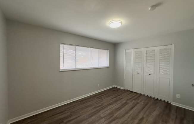 an empty living room with a window and a closet