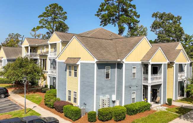 an apartment building with blue and yellow siding and a parking lot