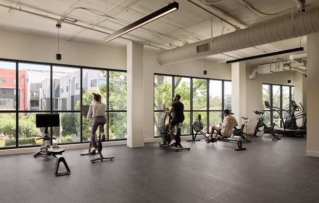 A gym with people exercising and a view of the city.