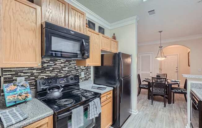 A kitchen with black appliances and wooden cabinets.