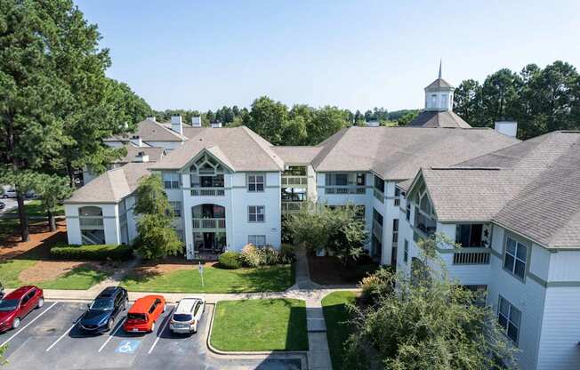 A white building with a tower is surrounded by a parking lot.