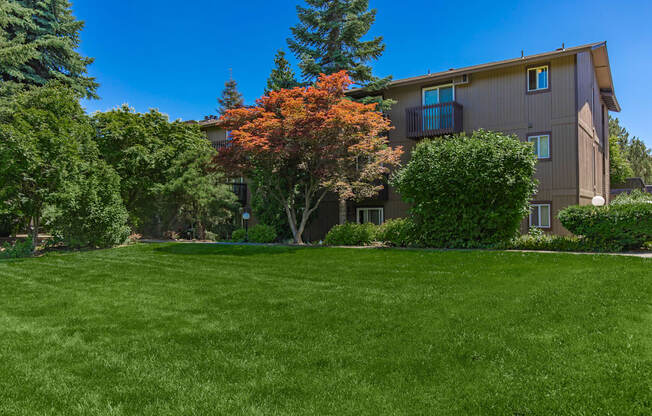 an apartment building with green grass and trees in front of it at Lincoln Village Apartments, Washington