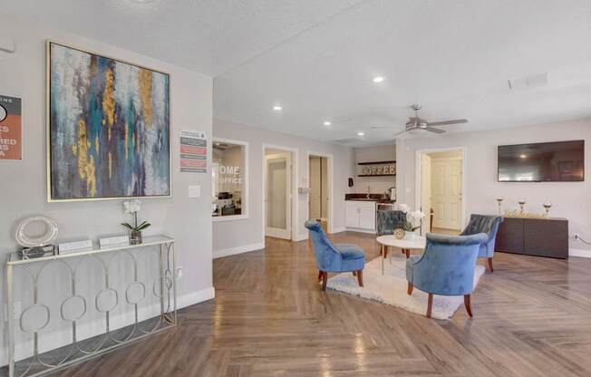 A living room with a blue chair and a painting on the wall.