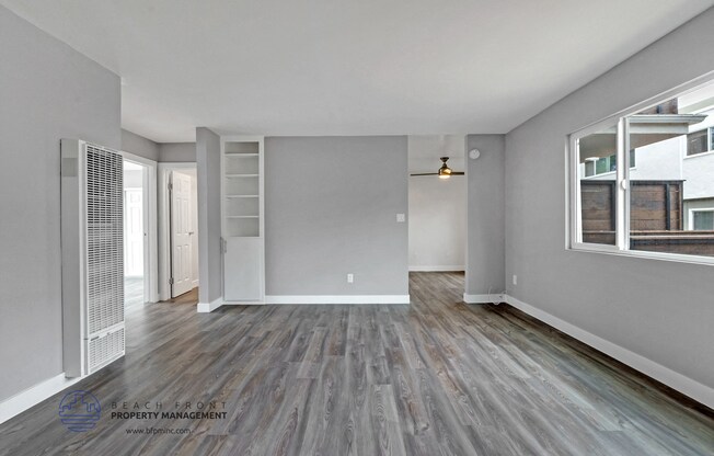 the living room of an apartment with grey walls and wood flooring