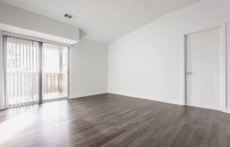 an empty living room with wood floors and a sliding glass door