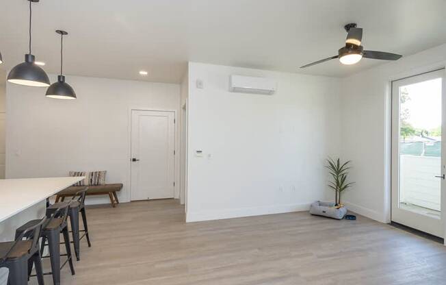 A room with a white table and chairs, a ceiling fan, and a plant.