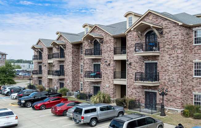 a brick apartment building with cars parked in the parking lot