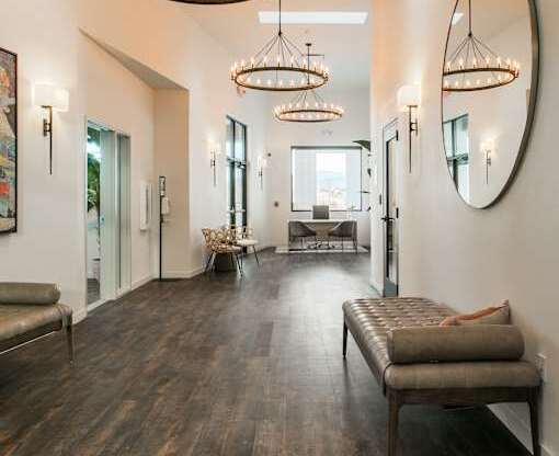 A hallway with a bench and a chandelier.