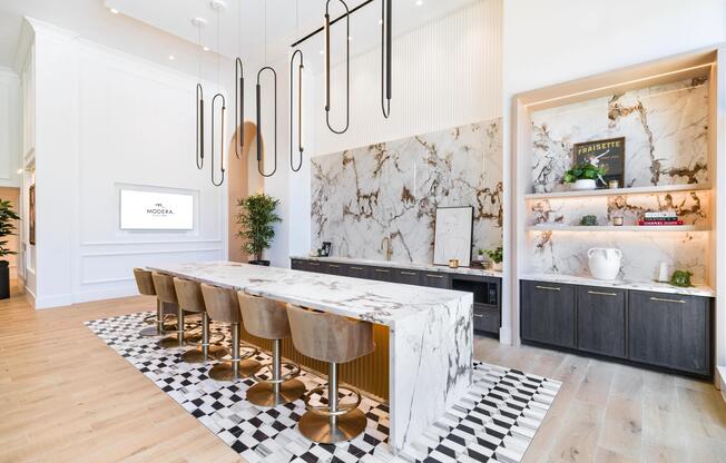 Community demonstration kitchen with a marble island, bar seating, and curated finishes designed for hosting, shared meals, and social gatherings.