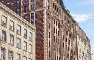A tall building with a red brick facade stands between two shorter buildings.
