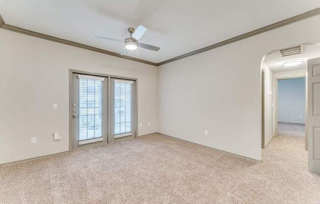 A room with a ceiling fan and carpeted floor.