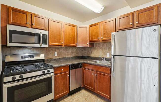 A kitchen with wooden cabinets and a stainless steel refrigerator.