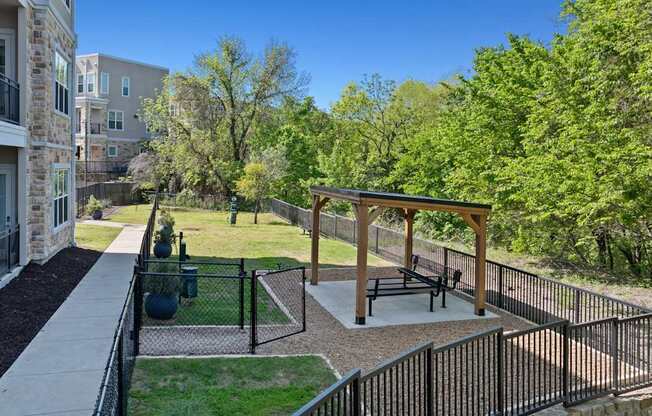 A patio with a table and chairs is surrounded by a black fence.