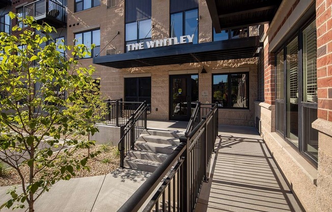 The Whitley building has a black railing and a tree in front of it.