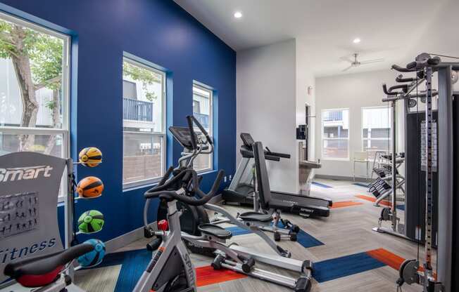 Fitness center at Stadium 700 Apartments in Arlington, TX with cardio machines, weights, and exercise balls