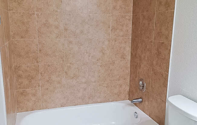 A white toilet sits next to a bathtub in a bathroom.