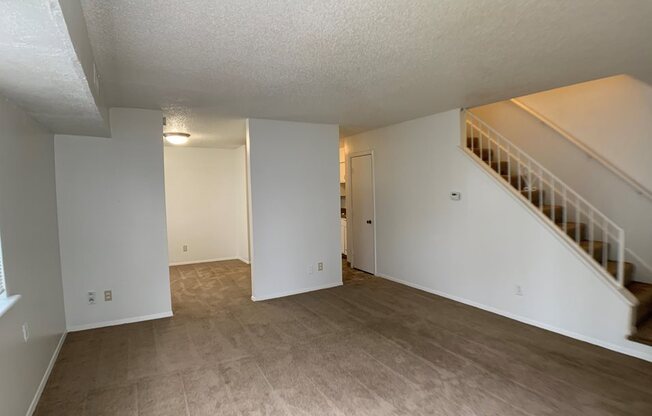 Large carpeted living room with stairs