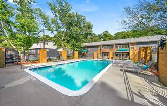 A large outdoor swimming pool surrounded by trees and a building.