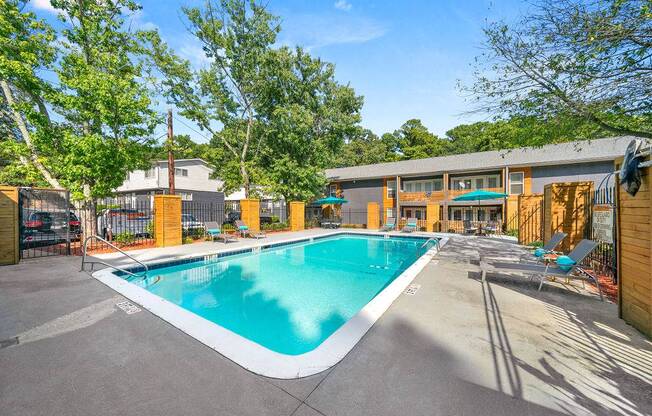 A large outdoor swimming pool surrounded by trees and a building.