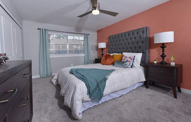 One bedroom in Watermarc two-bedroom apartment in lakeland, FL, with luxury carpeting, salmon accent wall, and large window with blinds.