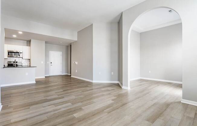 A spacious room with wooden flooring and a large archway.