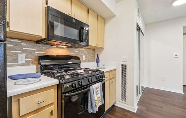 A kitchen with a black stove top oven and a black microwave above it.