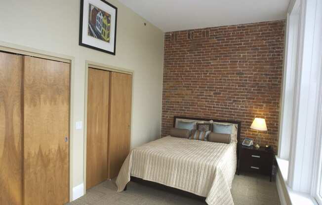 a bedroom with a bed and a brick wall at The Granite Works Apartments , New York