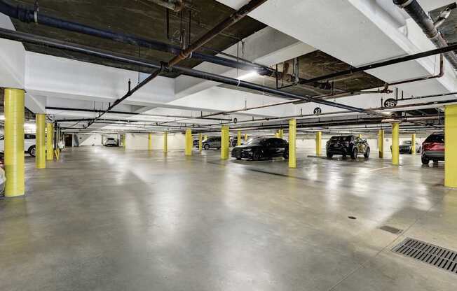 A parking garage with cars parked and yellow poles.