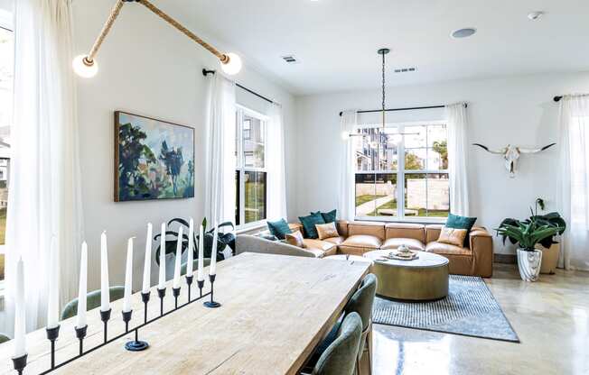 Living room and dining room with a wooden table and a large window at The Parker Austin, Pflugerville, TX