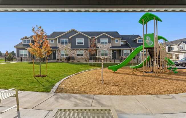 a playground with a green slide in front of an apartment building