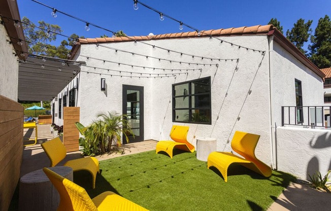 a backyard with yellow chairs and a white house at La Jolla Blue, San Diego