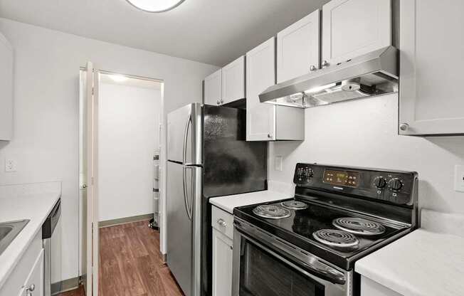 A black stove top oven in a kitchen with white cabinets.