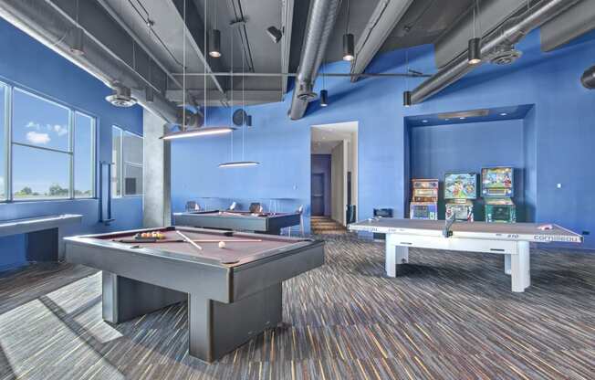 a games room with two pool tables and arcade games