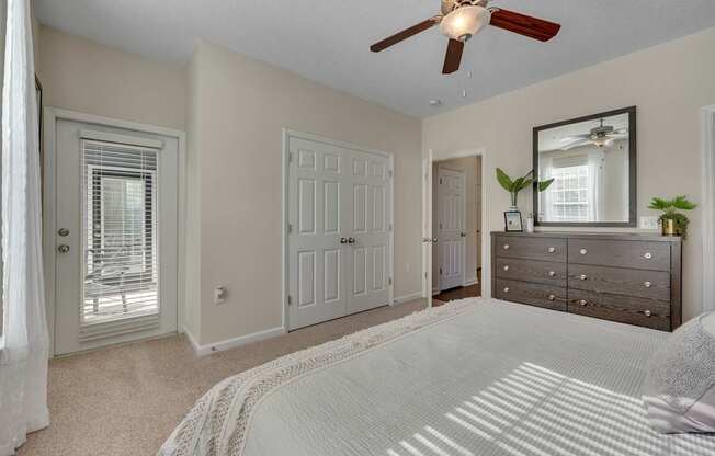 A bedroom with a white bedspread and a ceiling fan.