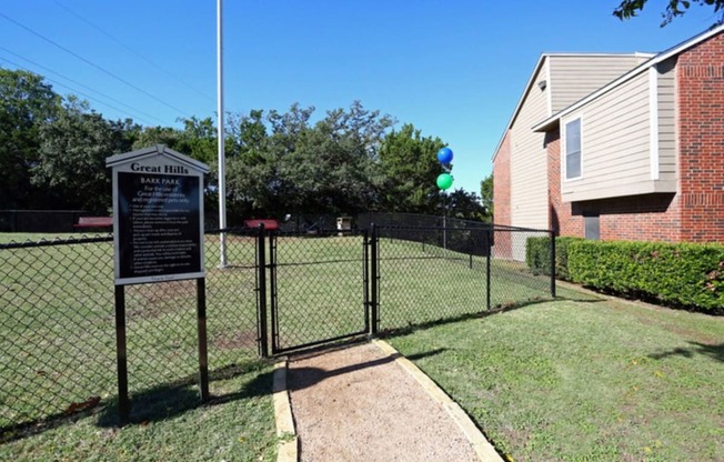 a dog park with a fence and a sign in front