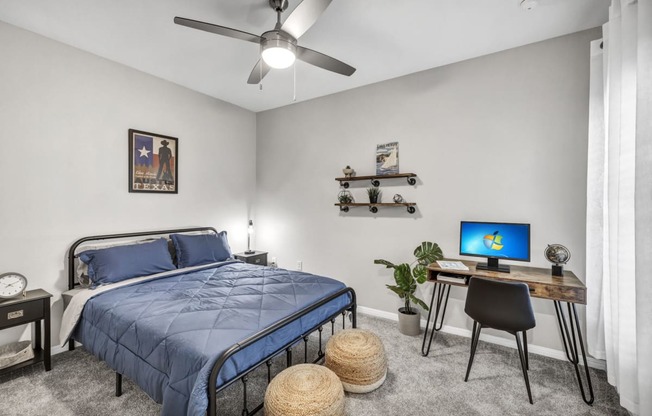 a bedroom with a bed and a desk with a computer